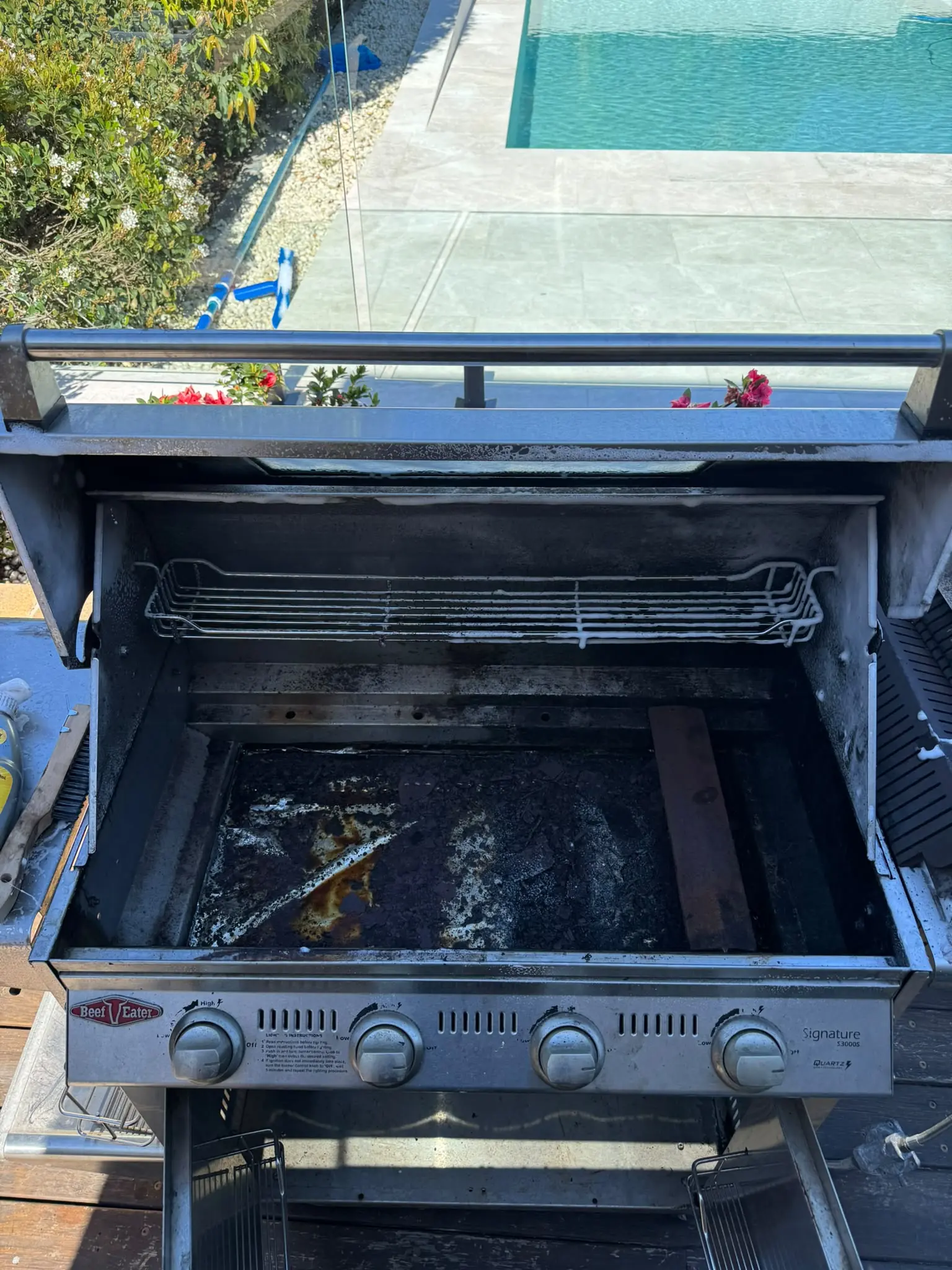 Open BeefEater four-burner BBQ showing grease and cooking residue before cleaning in Putney