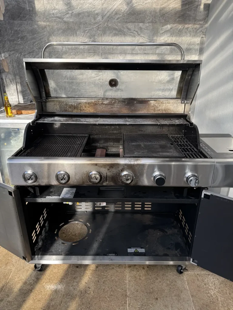 Lower cabinet of freestanding BBQ after removal of accessible grease and debris