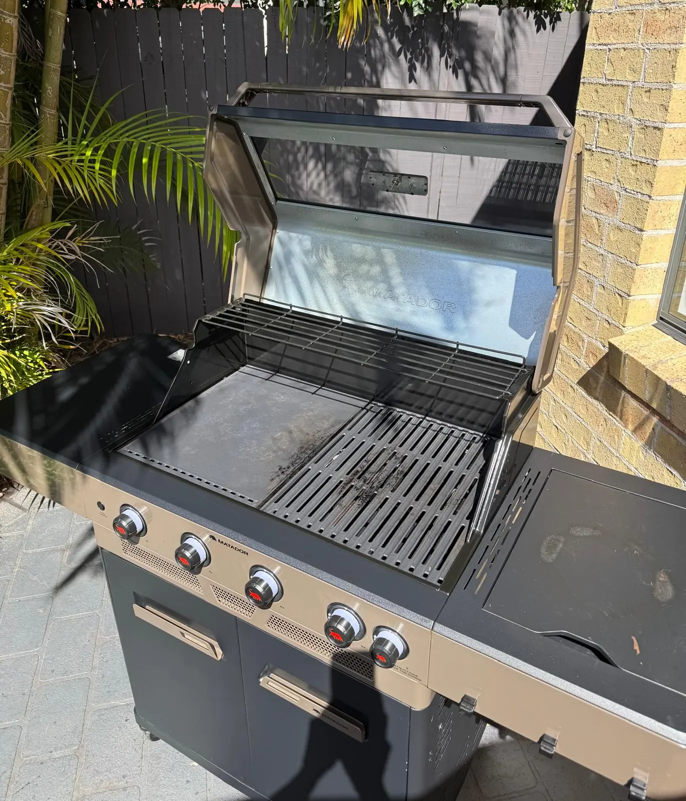 Open Matador Spark four-burner BBQ showing cleaned cooking surfaces and accessible interior in Narraweena