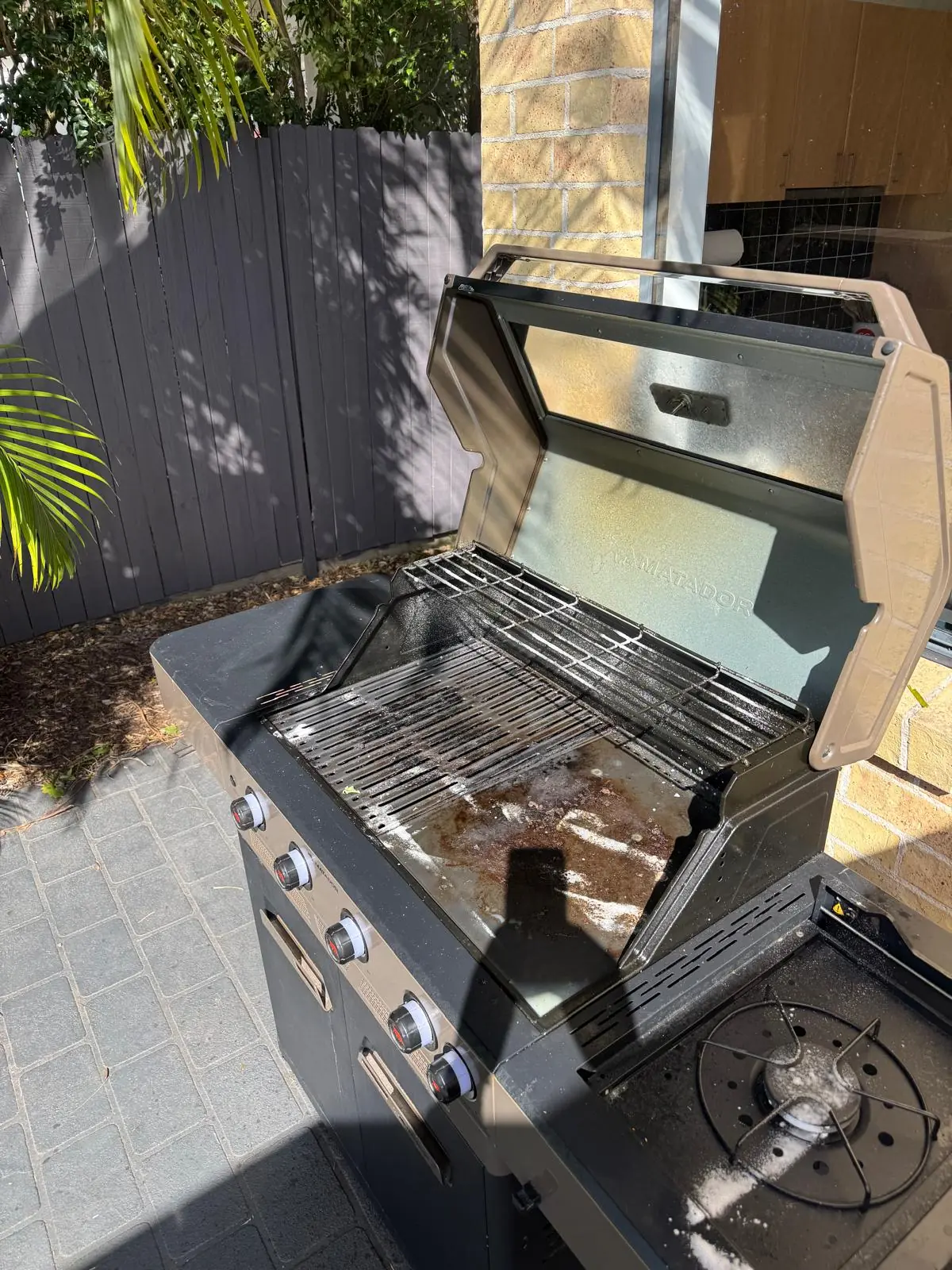 Open Matador Spark four-burner BBQ showing grease and cooking residue before cleaning in Narraweena