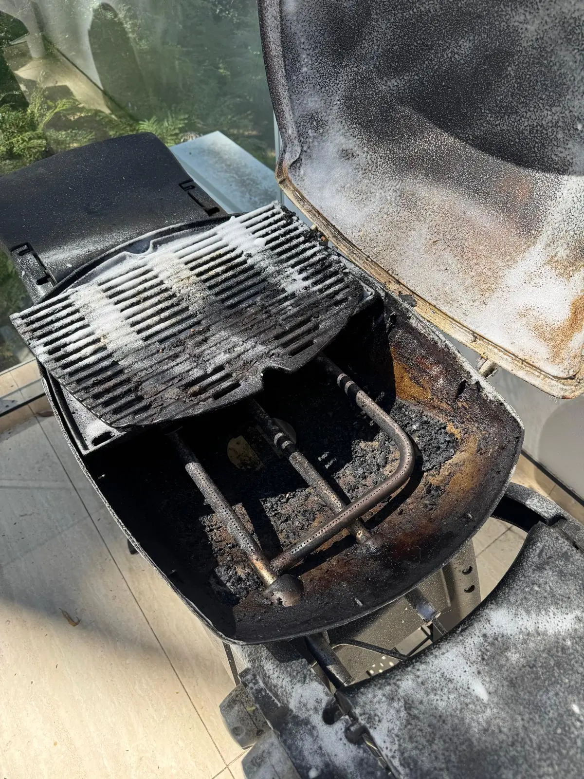 Weber Q BBQ interior in Ryde with cooking plate lifted to show accumulated residue
