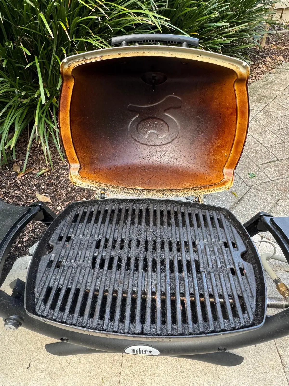 Open Weber Q1200 BBQ in Mosman before cleaning, with residue on the cooking grill and lid interior